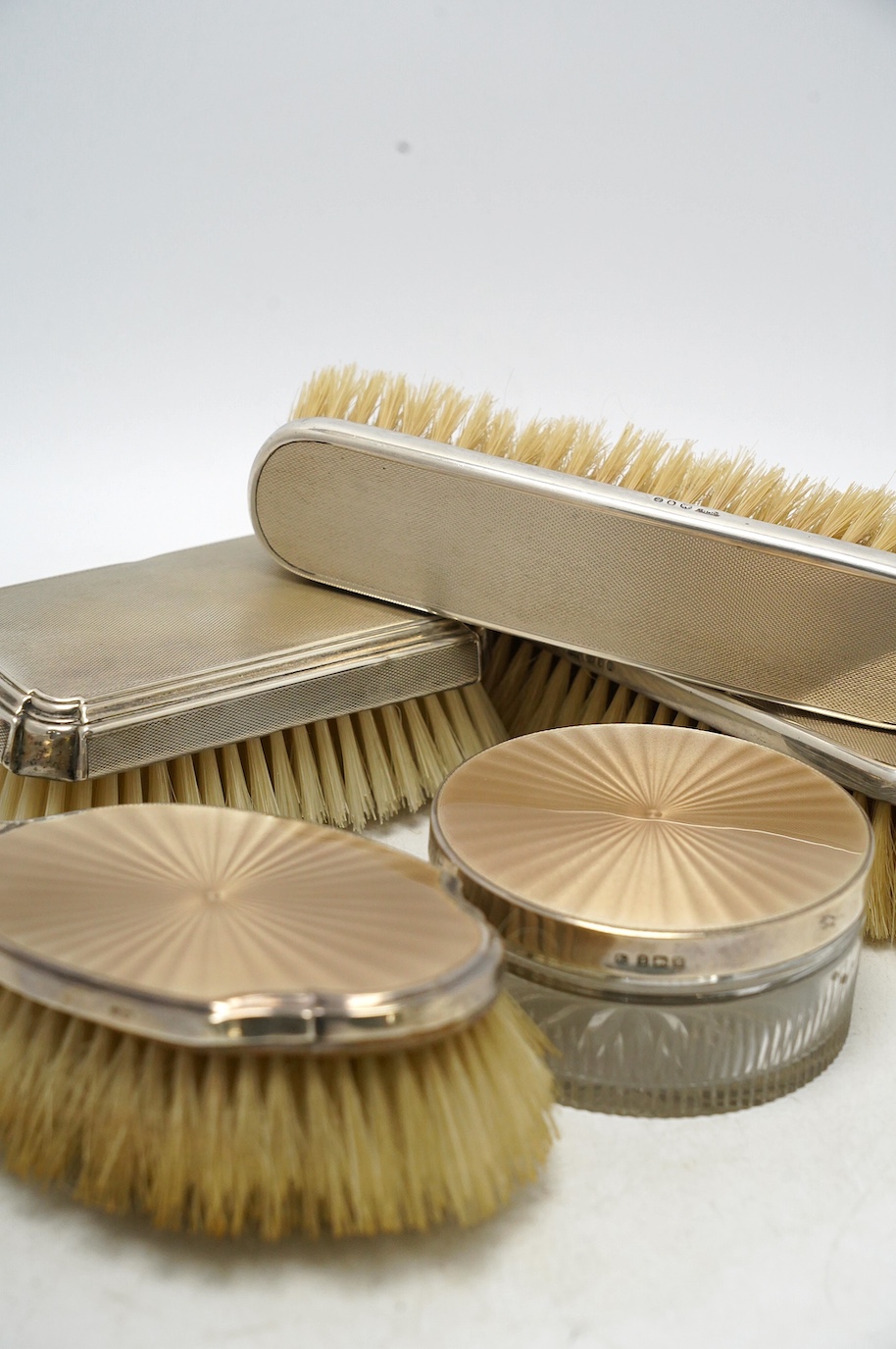 Nine assorted mid 20th century silver mounted dressing table items including a hand mirror, brush and powder jar with enamel, jar diameter 86mm. Condition - poor to fair
